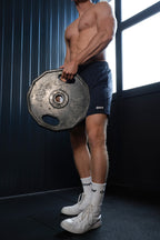 Man lifting a barbell plate in a gym setting On My Weights - OMW