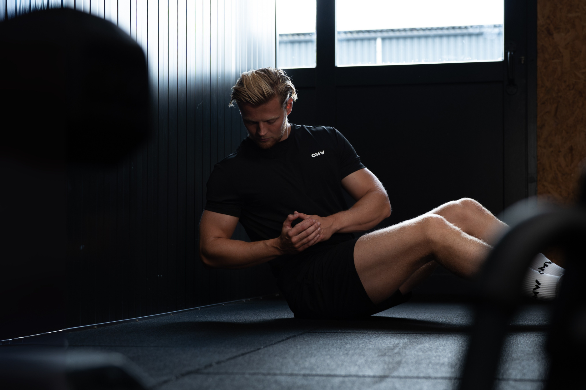 Man training in gym wearing black On My Weights athletic shirt during core workout.