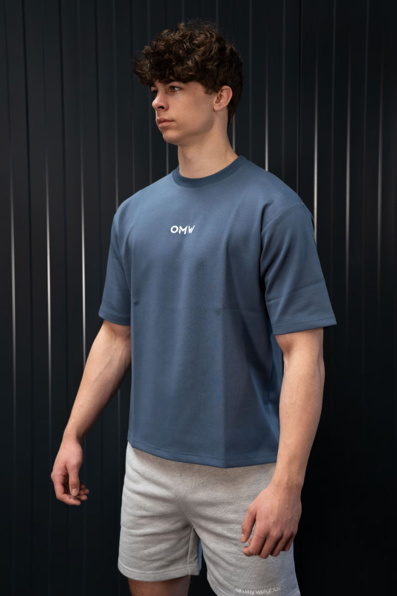 Persoon met een blauw T-shirt met een logo op een zwarte achtergrond.