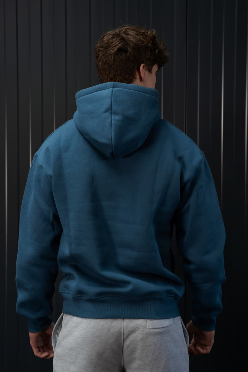 Persoon met een blauwe sport hoodie voor een zwarte achtergrond met strepen die verticaal gaan.