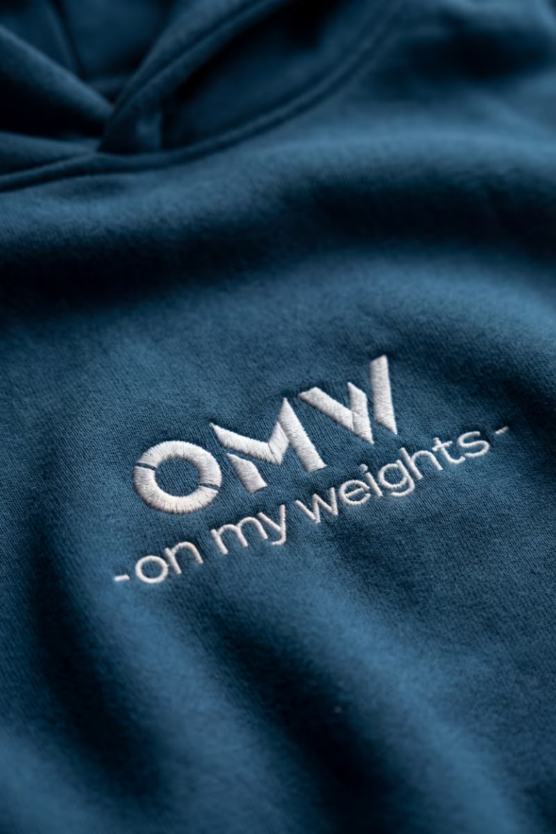 Blauwe hoodie met de geborduurde tekst 'OMW - on my weights'