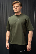 Man met een groen T-shirt met tekst op een donkere achtergrond.