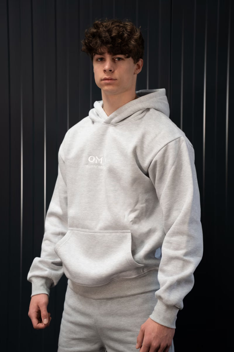 Persoon met een grijze On My Weights hoodie voor een zwarte achtergrond.