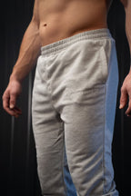 Grijze joggingbroek met een merklogo op een zwarte achtergrond.