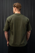 Man met een groen T-shirt tegen een zwarte achtergrond