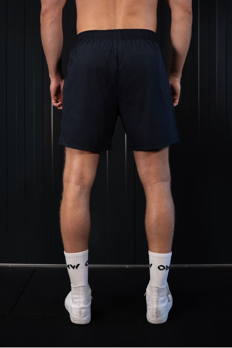 Persoon met zwarte korte broek en witte sokken op een zwarte achtergrond