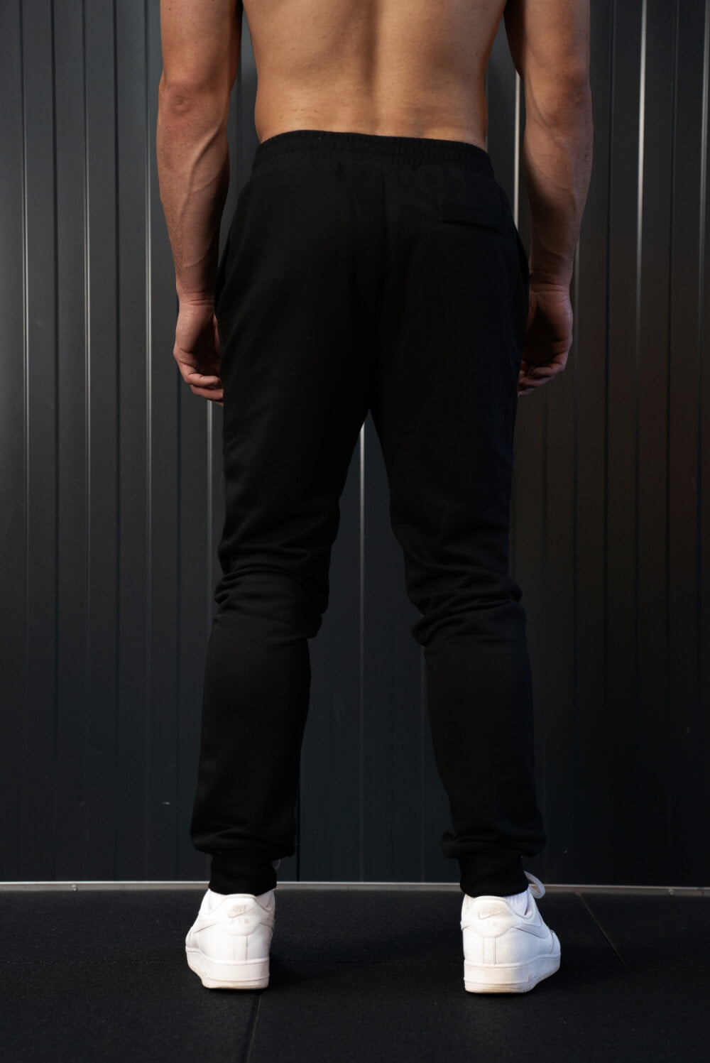 Back view of man wearing black On My Weights joggers – zwarte heren joggers met tapered fit en elastische tailleband.
