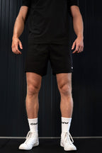 Man wearing lightweight black On My Weights shorts – ademende gymshorts voor heren, sportieve look met OMW sokken.