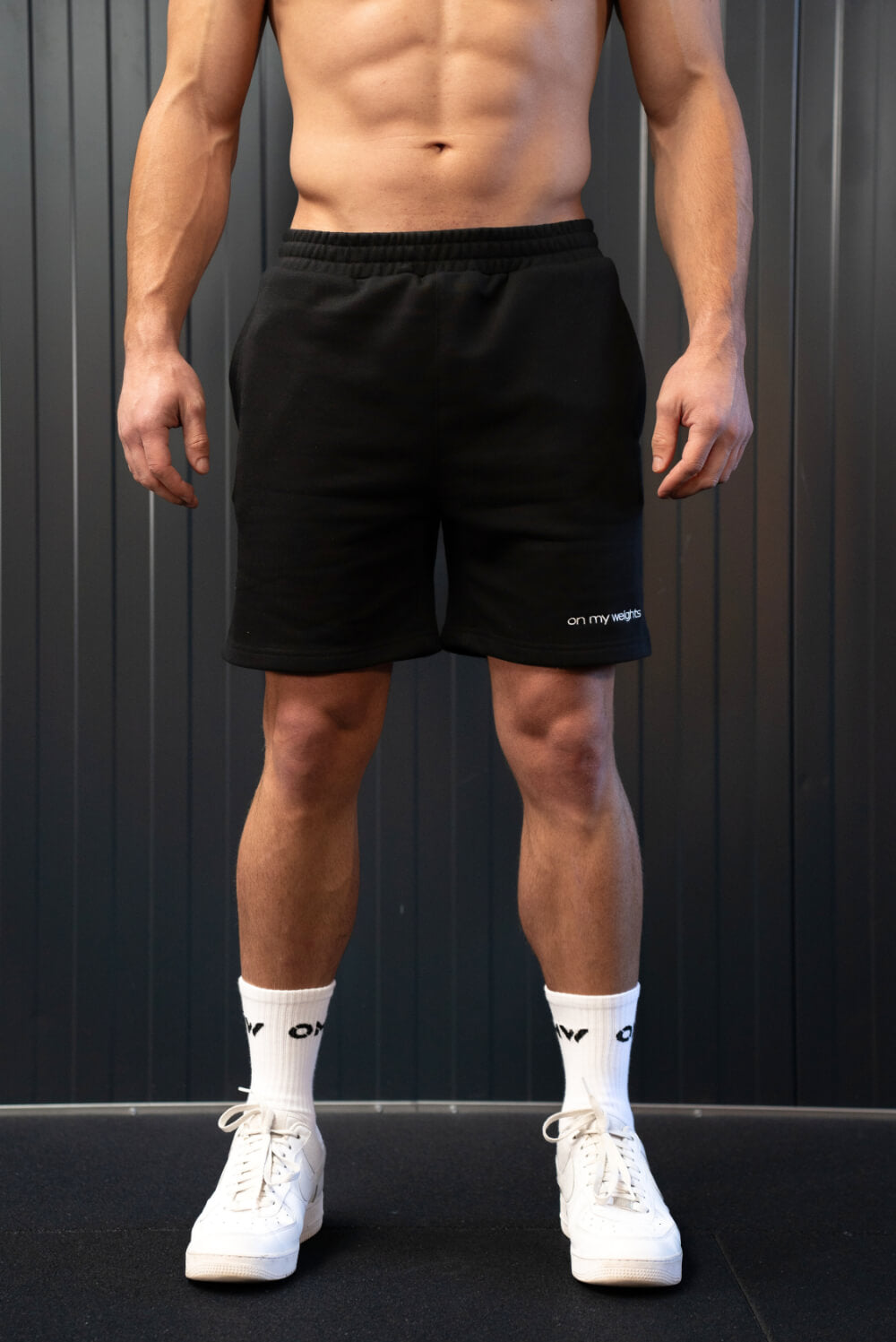 Man wearing black On My Weights shorts – comfortabele zwarte sportshorts voor heren met subtiel logo, gymwear style.
