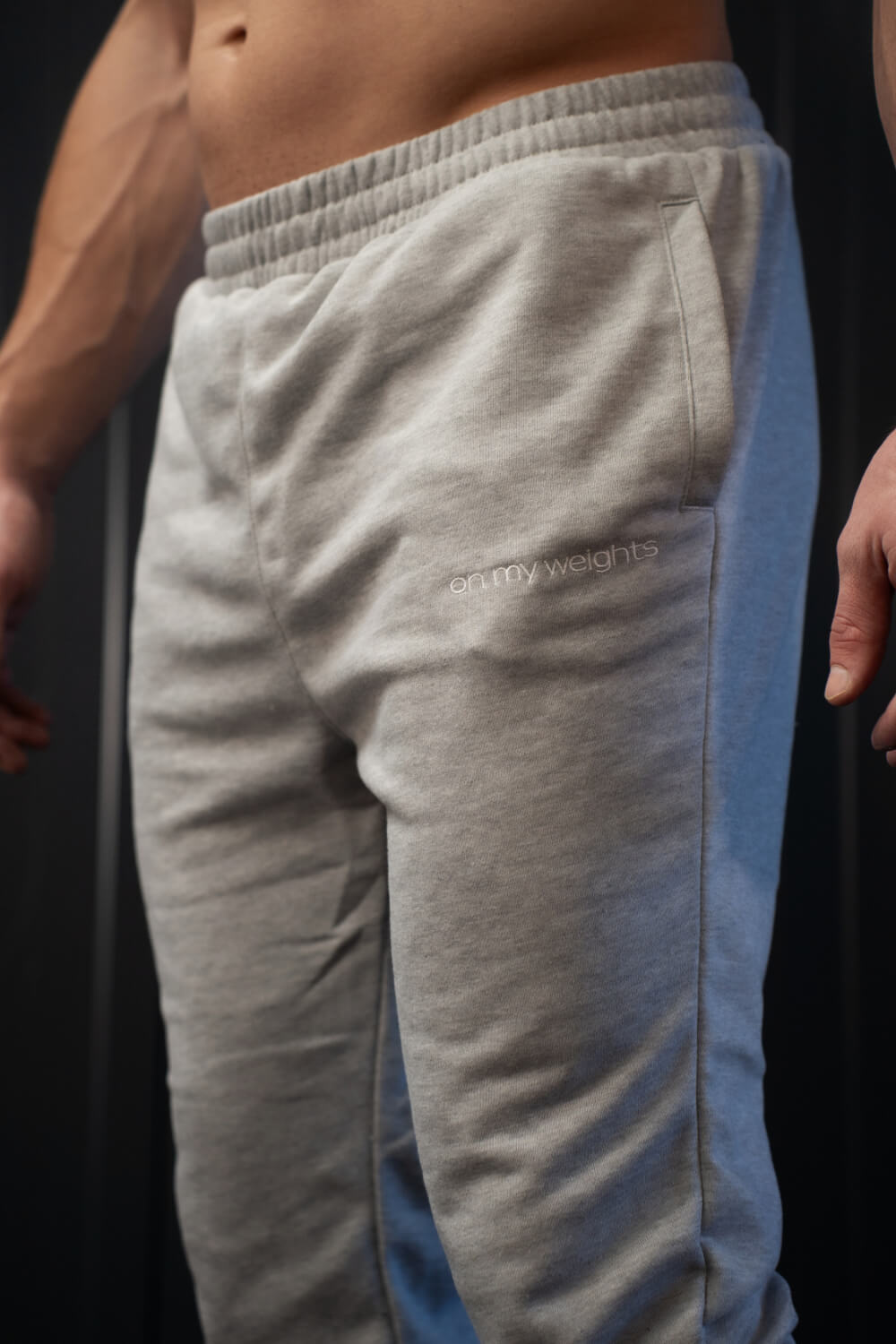 Close-up of On My Weights logo on grey joggers – detail van zachte katoenen stof en subtiele borduring.
