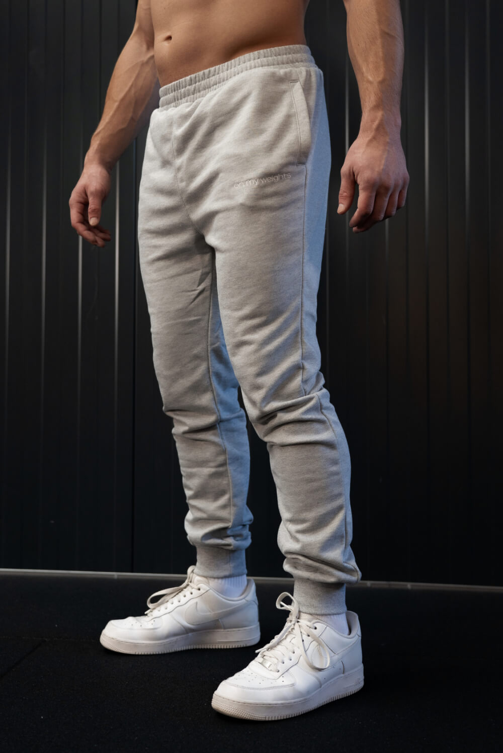 Model in grey On My Weights joggers – tapered fit, zachte stof en subtiel logo voor een moderne sportstijl.