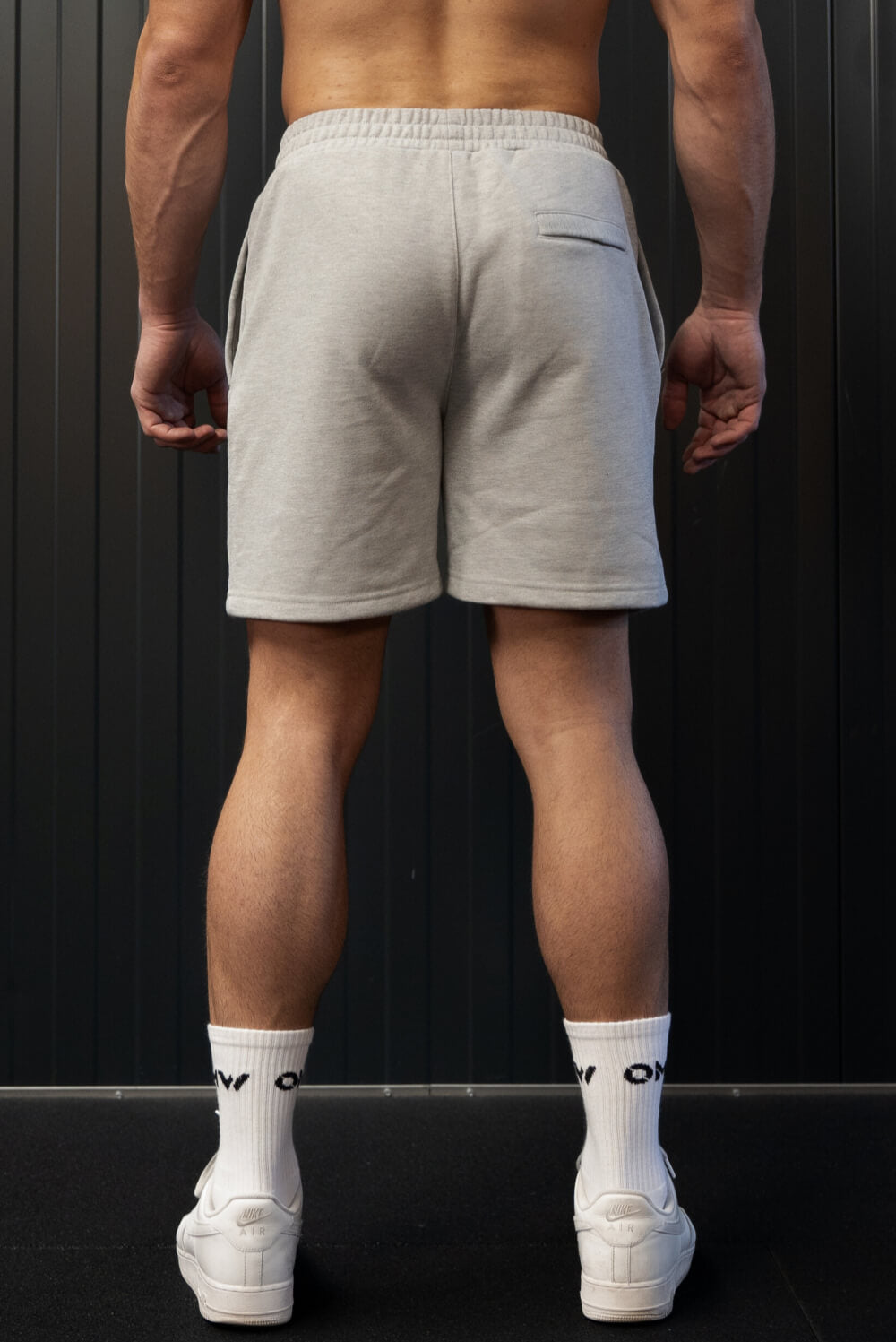 Back view of man wearing grey On My Weights shorts – grijze heren short met elastische tailleband en moderne pasvorm.