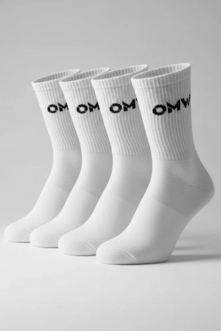Vier witte sokken met 'OMW' op de bovenkant voor een grijze studio achtergrond