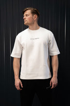 Man met een wit T-shirt met tekst op een zwarte achtergrond.