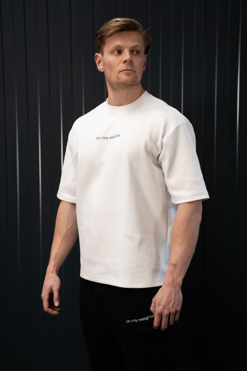 Man met een wit T-shirt met tekst op een zwarte achtergrond.